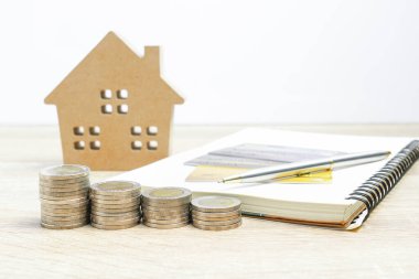 Ev modeli ve bankacılık konsepti için masanın üzerinde madeni paralar olan not defteri.