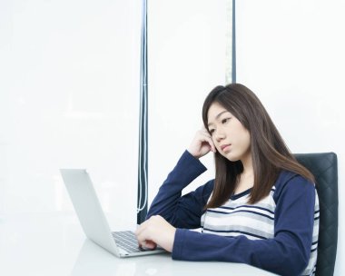 Oturma odasında oturan genç kız öğrenci bilgisayarla internetten öğreniyor.