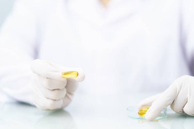 Bilimadamlarının elleri nitril lateks eldivenler takıyor. Omega 3 kapsülünü laboratuarda deneyler yapıyor.