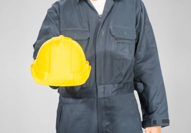 Gri arka planda izole edilmiş sarı baret tutan mavi kapaklı işçiler giyiniyor.