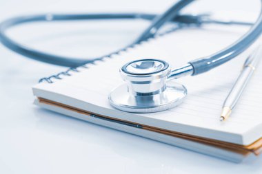 Boş not defterindeki steteskopu tıbbi konsept olarak kapat