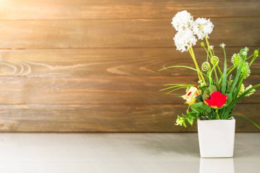 Ahşap duvarlı masa üzerinde yapay çiçek vazosu buketi