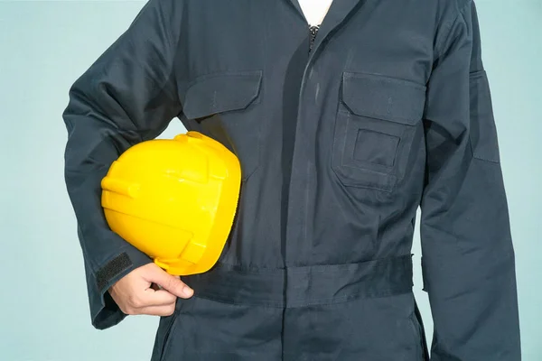 Trabalhador Macacão Azul Segurando Chapéu Amarelo Isolado Fundo Azul — Fotografia de Stock