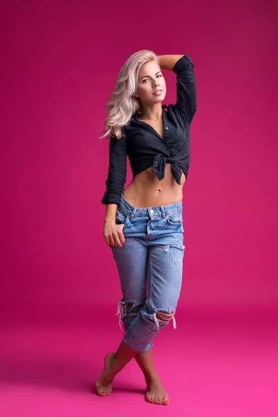 Vrouw in top en jeans tegen roze achtergrond — Stockfoto