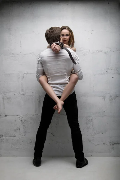 Young beautiful couple shot embracing against wall — Stock Photo, Image