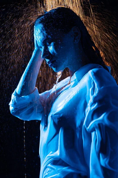 Sexy woman in wet shirt having shower in the dark room profile waist up portrait