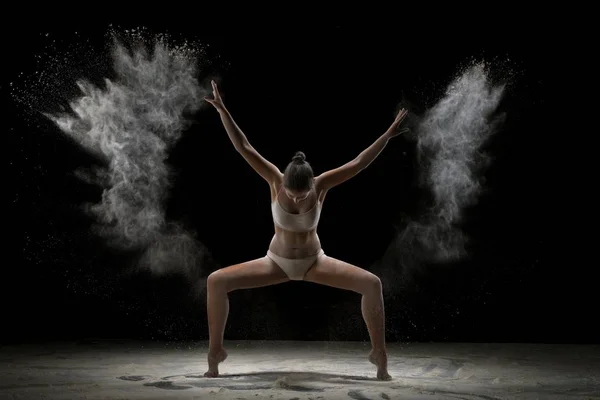 Jong meisje dansen in een uitbarsting van wit poeder — Stockfoto