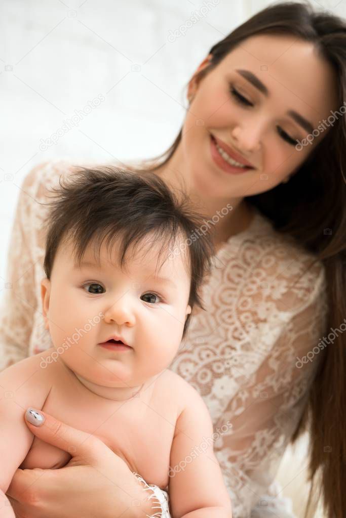 Pretty woman holding baby boy in her arms view