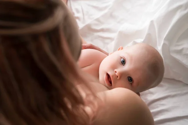 Малыш в постели смотрит на свою мать — стоковое фото