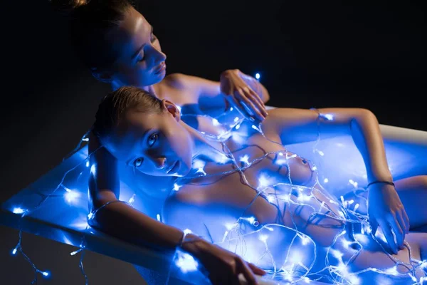 Naken modeller i badet i garland lights i mörkret — Stockfoto