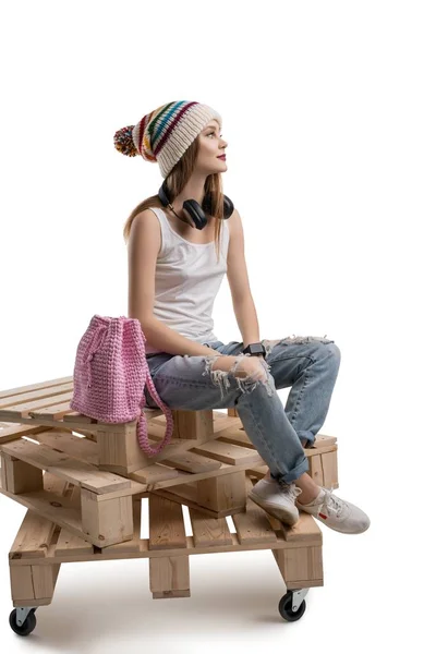 Μοντέρνα γυναίκα που κάθεται στις ξύλινες παλέτες — Φωτογραφία Αρχείου