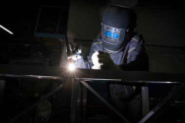 Argon kaynak yapıyor yüzü kalkan işçi görünümünü
