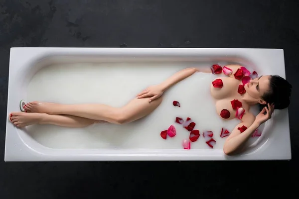 아름 다운 여자와 장미 꽃잎 목욕 하는 데 — 스톡 사진