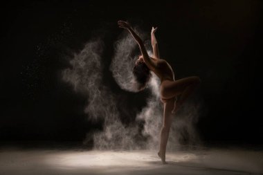 Beyaz toz bulutu içinde incelikle dans jimnastikçi