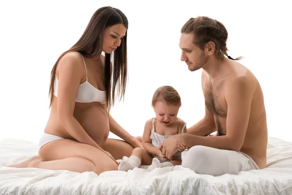 Family shot sitting on bed with their little son