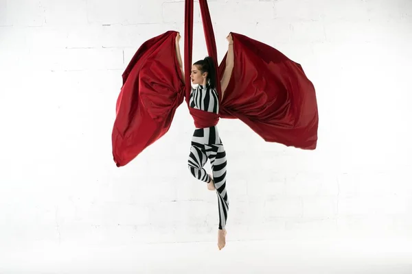 Тонкая гимнастка, изящно тренирующаяся на фоне ткани — стоковое фото