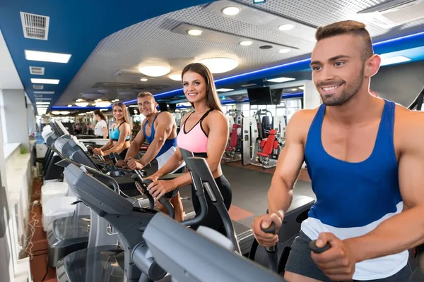 Jóvenes deportistas en simuladores en un gimnasio — Foto de Stock