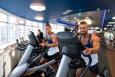 Spor salonunda simülatör kullanan genç erkekler.