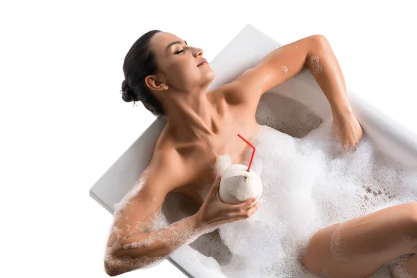 Prachtige brunette in schuim bad en cocktail — Stockfoto