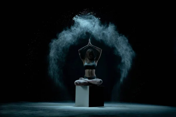 Танцівниця сидить на перехресті на темній сцені — стокове фото