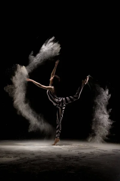Витончена жінка танцює у вибуху піску — стокове фото