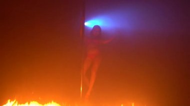 İç çamaşırlı esmer, ateşte striptiz yapıyor.