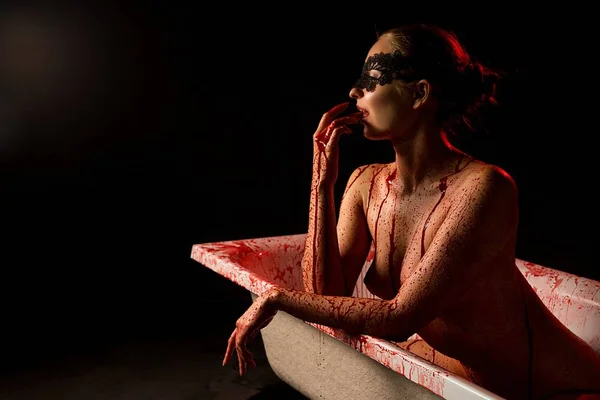 Nude woman in mask in bath with red stains — Stock Photo, Image