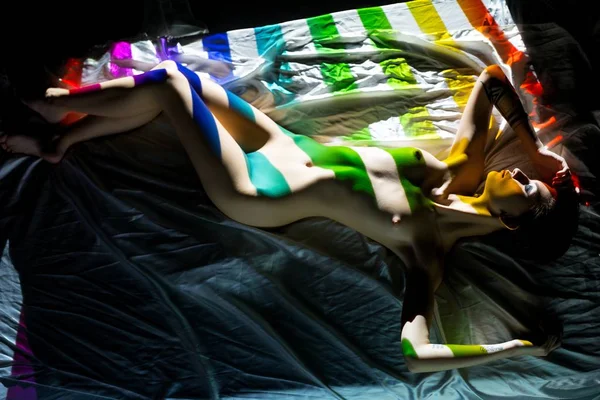 Mujer tranquila desnuda tumbada en la luz colorida — Foto de Stock