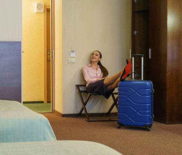 Hotel. Woman poses while puts her feet on suitcase — Stock Photo, Image