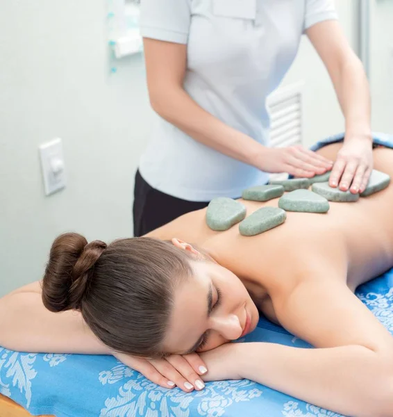 Красива дівчина отримує гарячий кам'яний масаж в спа-салоні — стокове фото