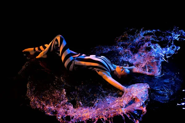 Девушка в обнаженном теле лежит в воде в темноте — стоковое фото