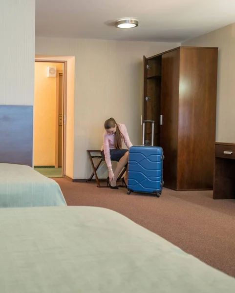 Szép asszony leveszi a cipőjét, szállodai szobában — Stock Fotó