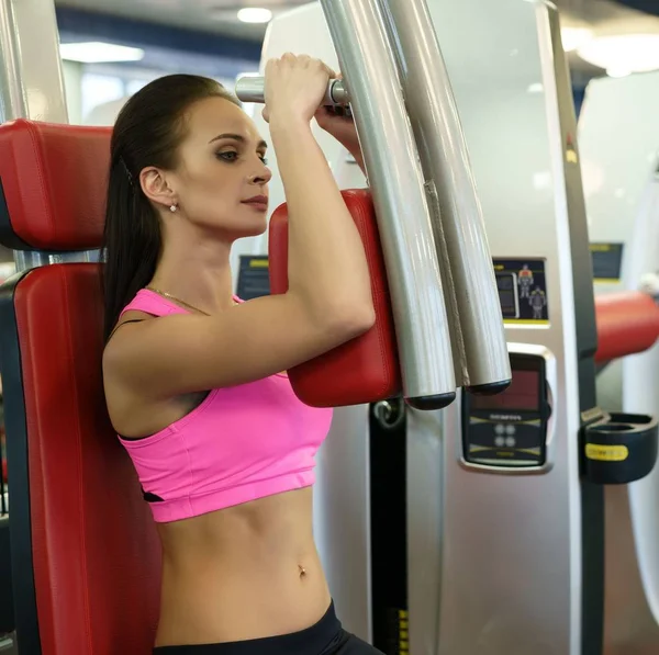 Hermosa joven haciendo ejercicio en simulador — Foto de Stock