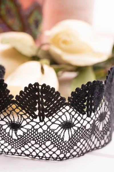 Black lace ribbon among flowers close up view — Stock Photo, Image