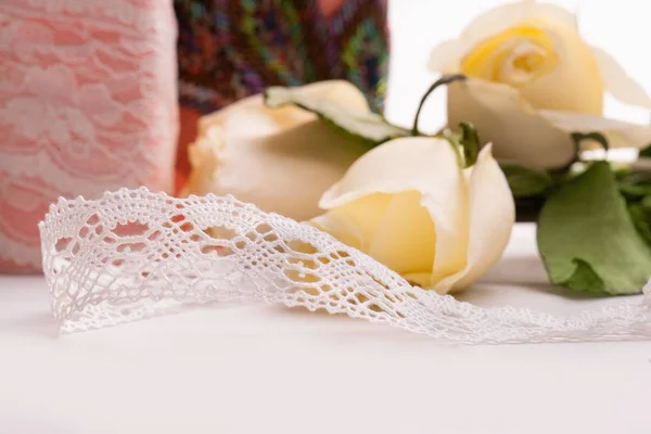 Handiwork lace ribbon on the table among roses — Stock Photo, Image