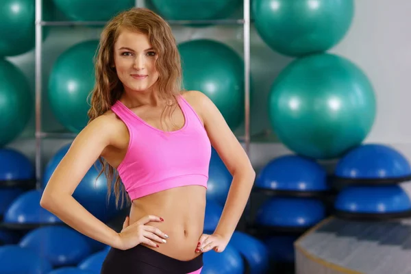 Meisje poses op achtergrond van stand met fitness ballen — Stockfoto