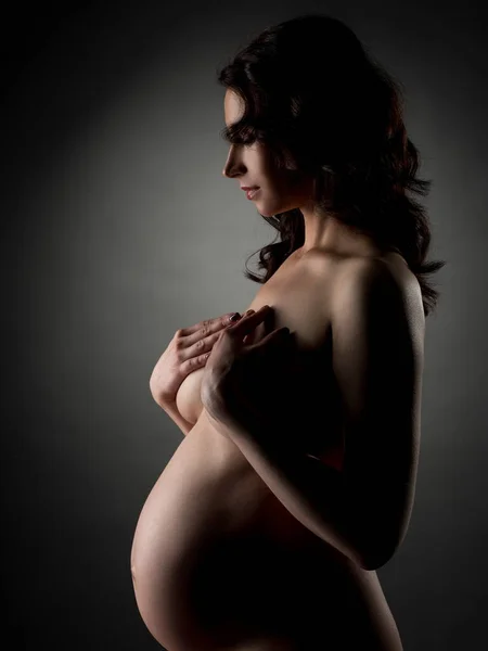 Seitenansicht einer schwangeren Frau, die nackt posiert — Stockfoto