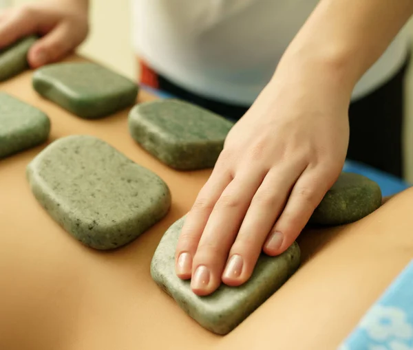 Masaje de piedra en spa, enfoque en la mano del terapeuta —  Fotos de Stock