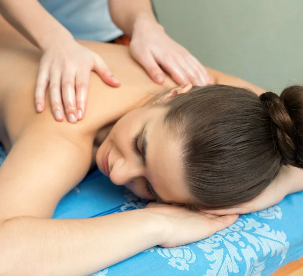 Jovem deitada de barriga para baixo tendo massagem — Fotografia de Stock