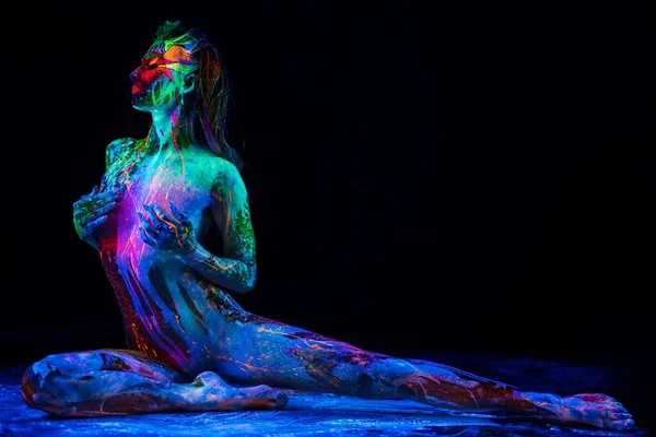 Girl with ultraviolet color pattern bodyart doing split — Stock fotografie