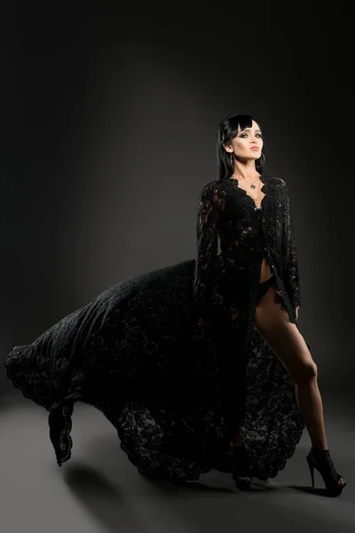Bruna sexy in mantello nero e vista biancheria intima — Foto Stock