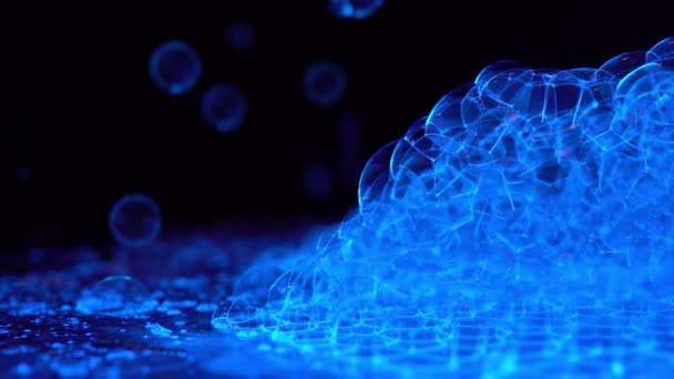 Ultra violet bubbles flying in the dark and landing on background — Wideo stockowe