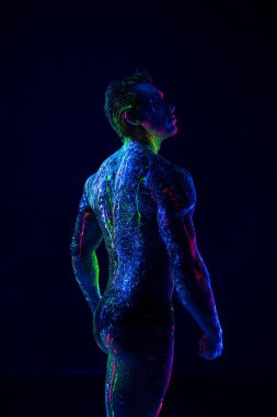 Karanlıkta ultraviyole neon vücut sanatıyla kaslı bir adam.