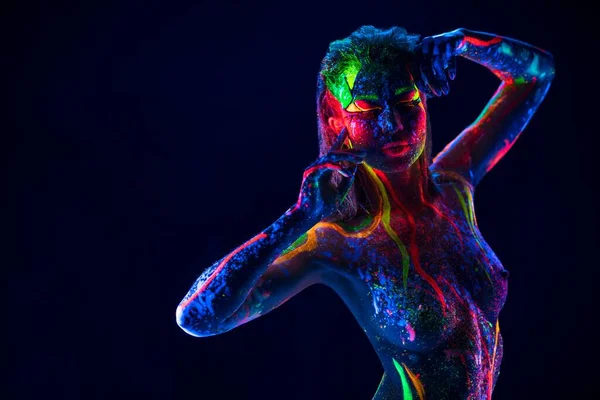 Красивая топлесс-женщина с неоновым ультрафиолетовым телом танцует в темноте — стоковое фото