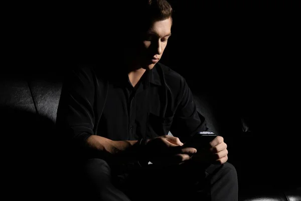 Hombre serio usando el teléfono inteligente en la habitación oscura —  Fotos de Stock