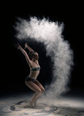 İç çamaşırlı, sportif orta yaşlı bir kadın yoga salonunda tozla poz veriyor.