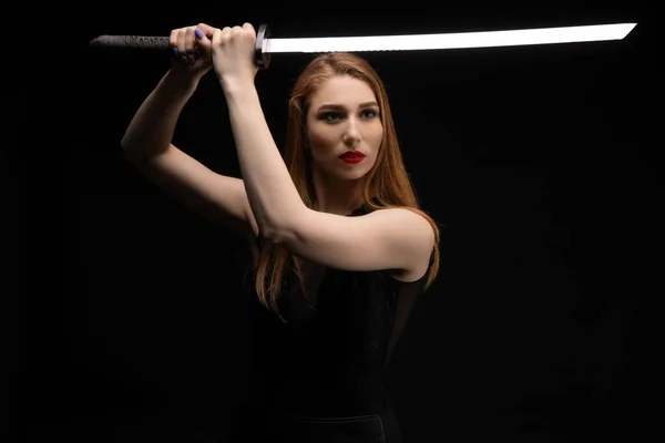 Junge Frau mit Schwert im dunklen Atelier — Stockfoto