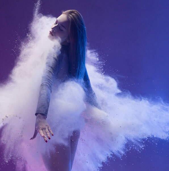Woman in pointe shoe in dust cloud and color light