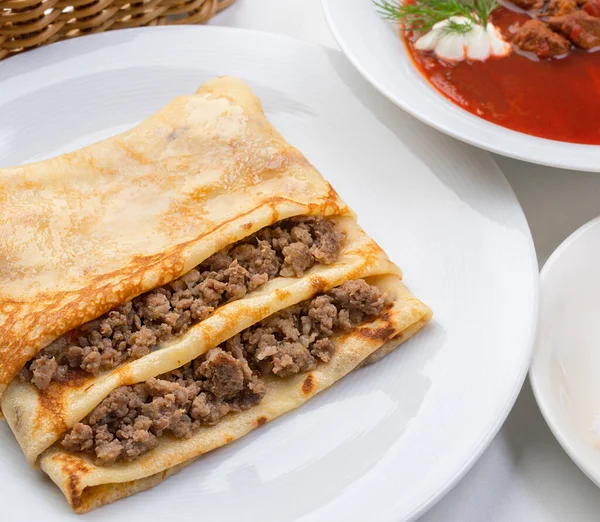 Pancake stuffed with meat and borsch with greenery