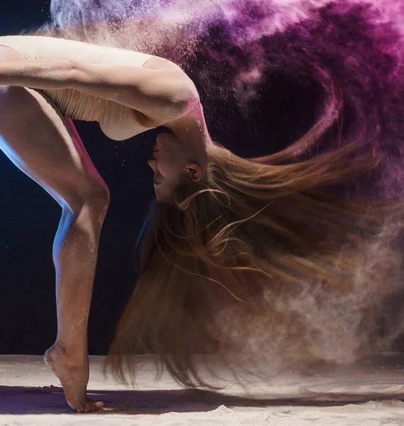 Půvabná gymnastka v oblaku barevného prachu — Stock fotografie